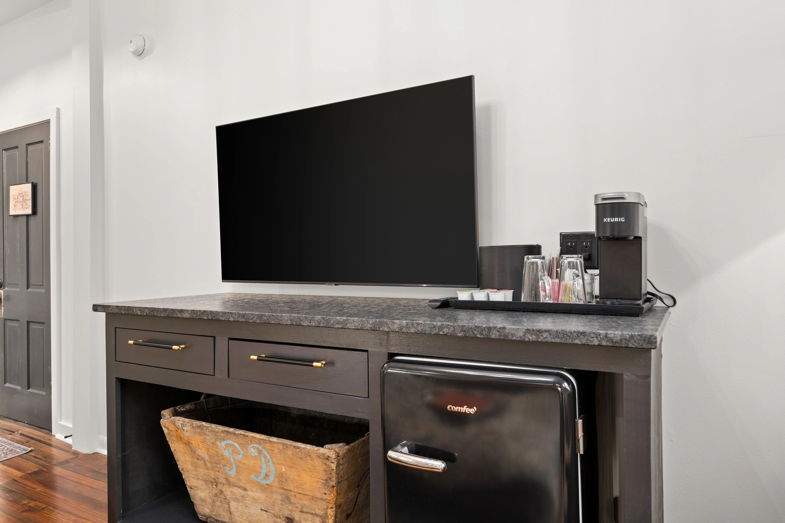 Modern TV setup with a coffee maker and mini fridge on a dark wooden console